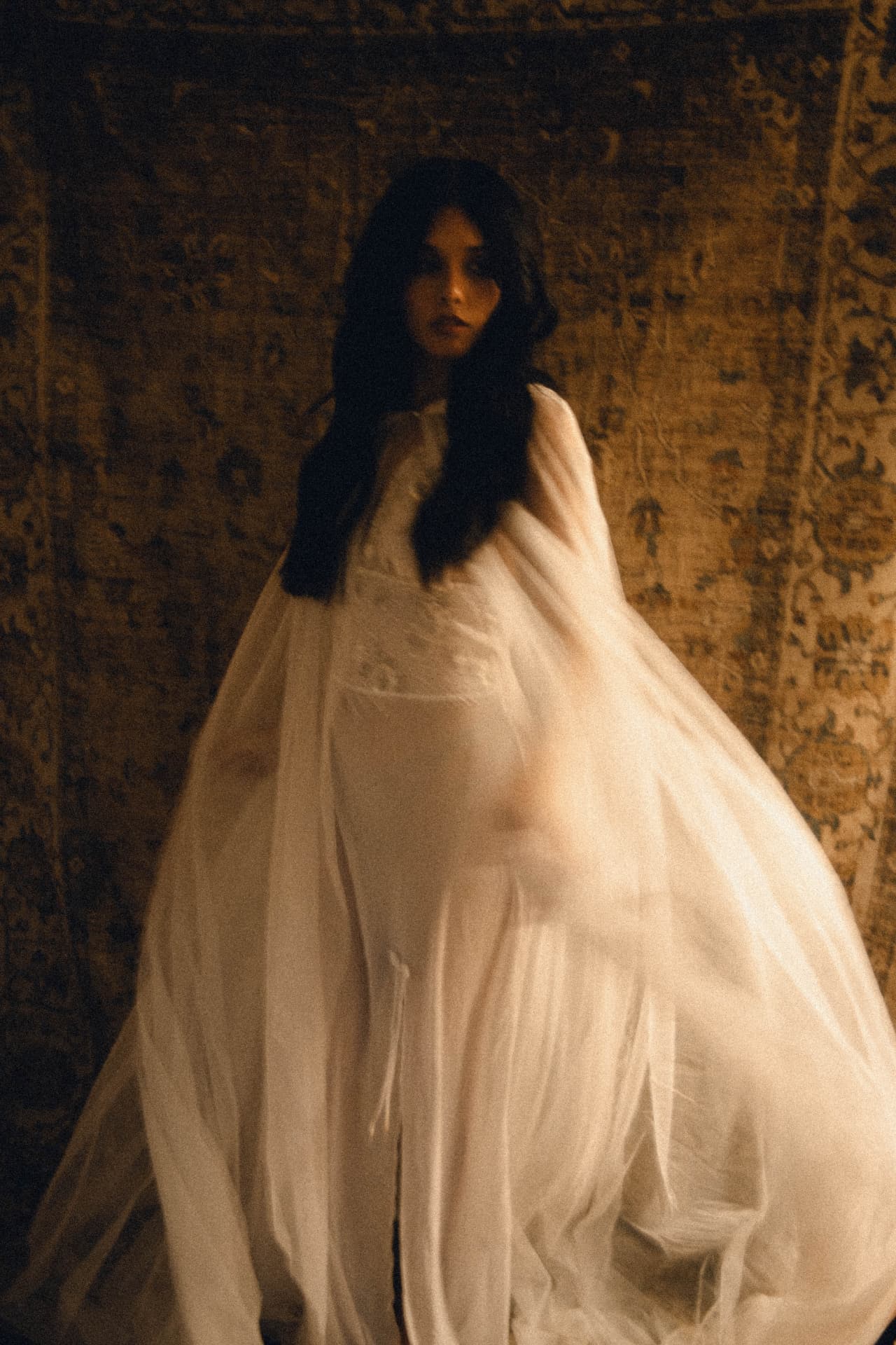 A bride standing beneath a billowing sheer veil