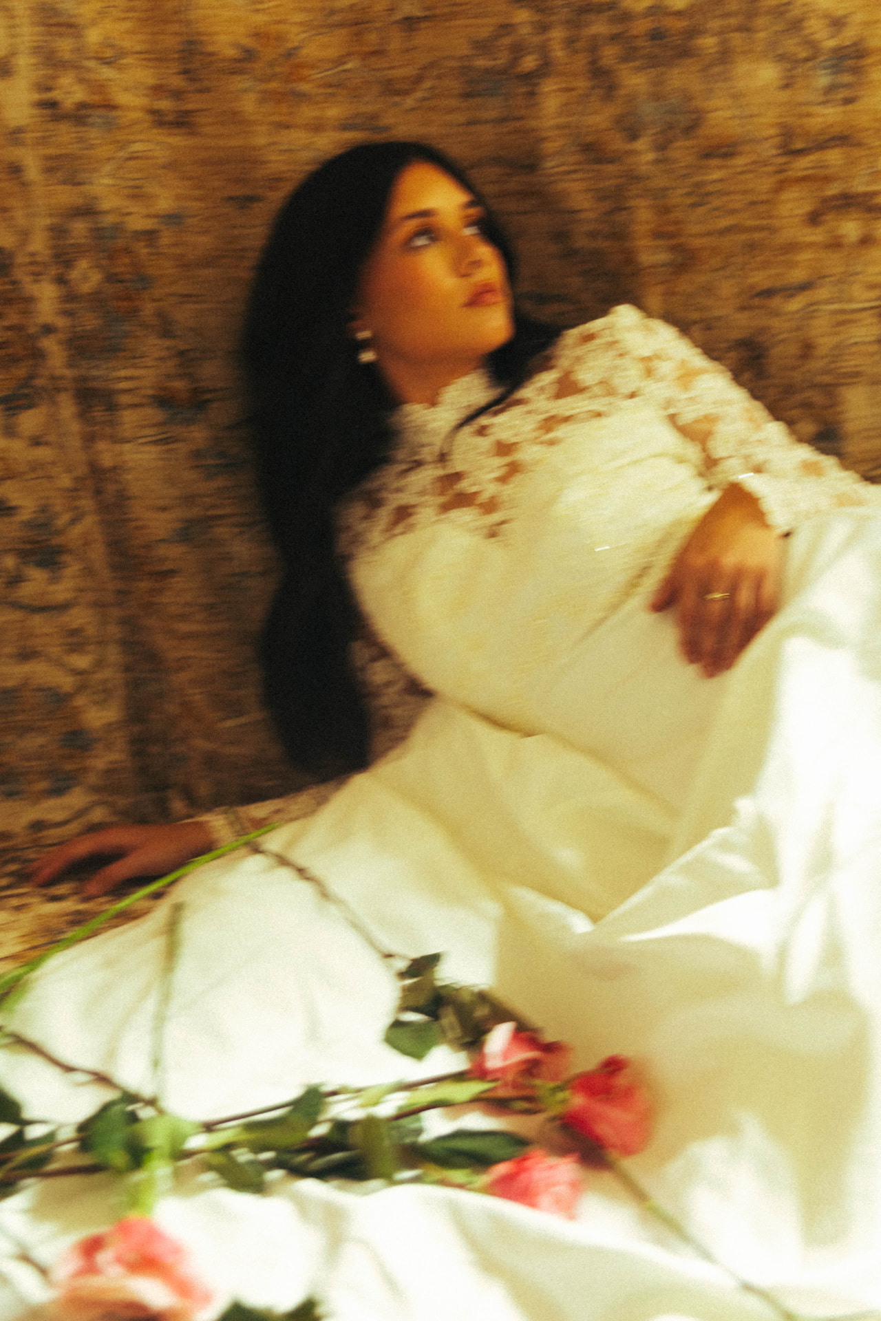 A bride reclining with pink roses across her dress