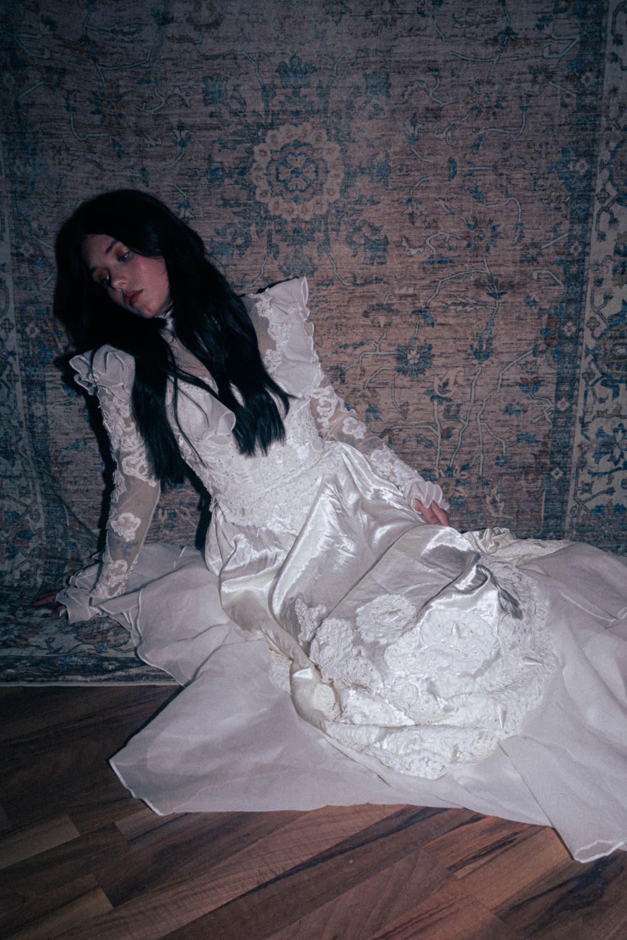 A bride reclining on the floor in a full-length ivory gown